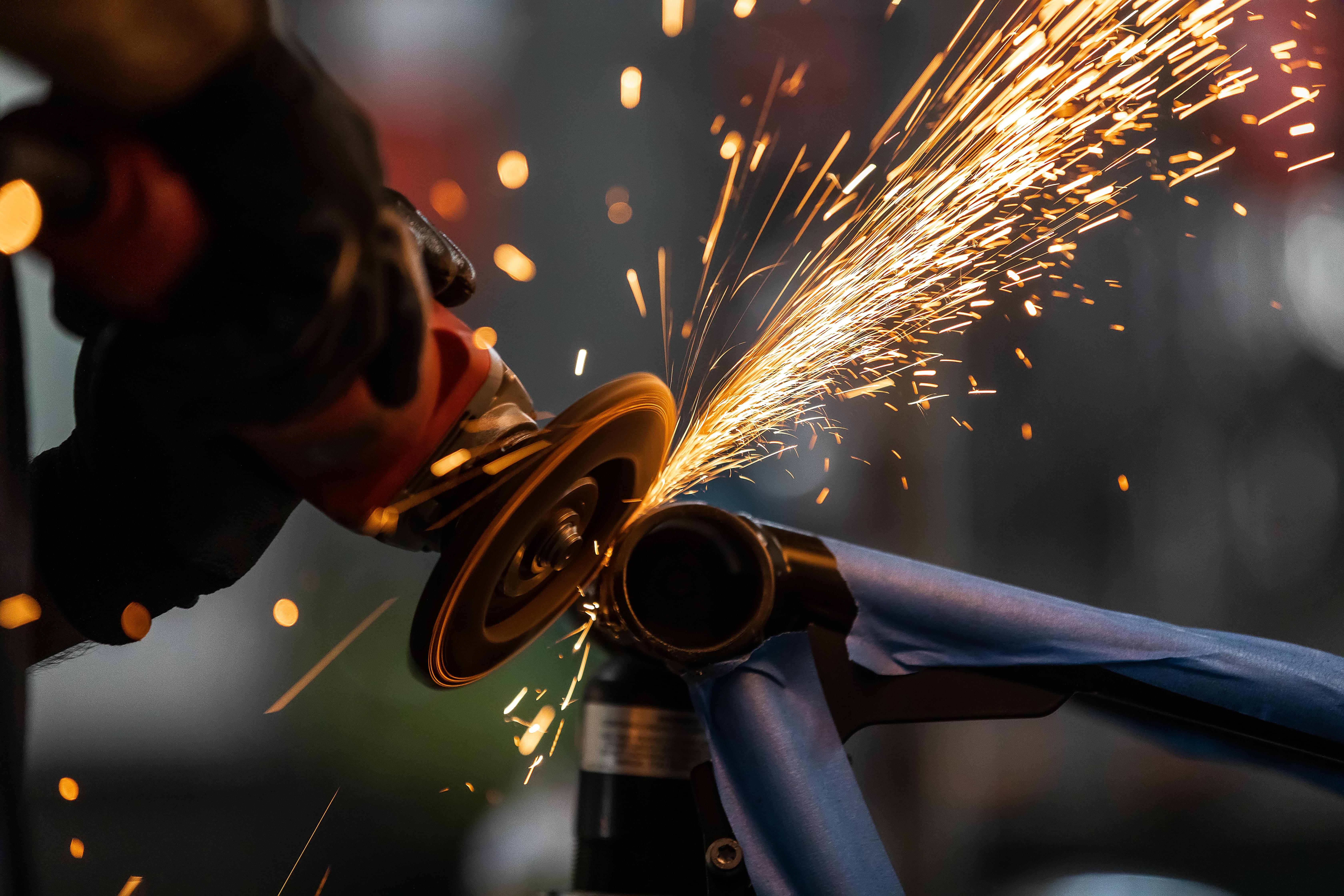 worker,cutting,,grinding,and,polishing,motorcycle,metal,part,with,sparks